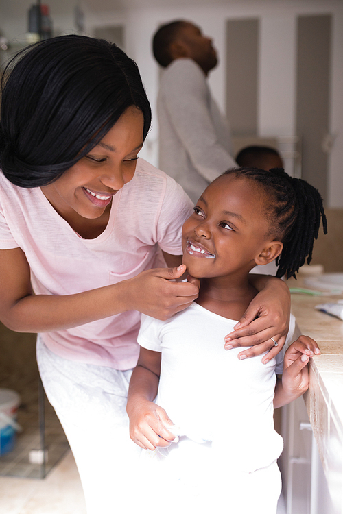 Smiling mother checking daughters teeth in bathroom at home