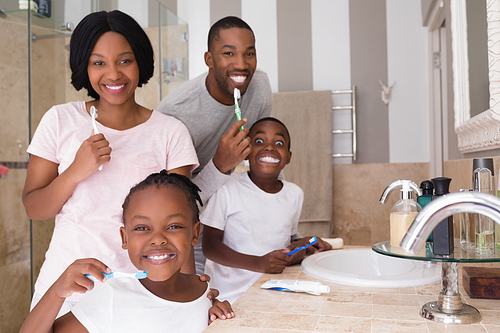 Portrait of happy family brushing teeth in bathroom at home