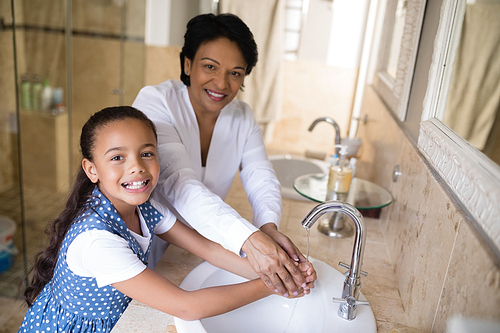 Portrait of grandmother and granddaughter washing hands at bathroom sink