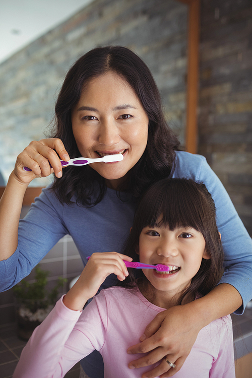 Portrait of mother and daughter brushing teeth in the bathroom