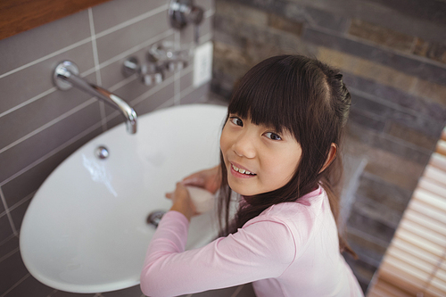 Portrait of girl washing hands in bathroom sink at home