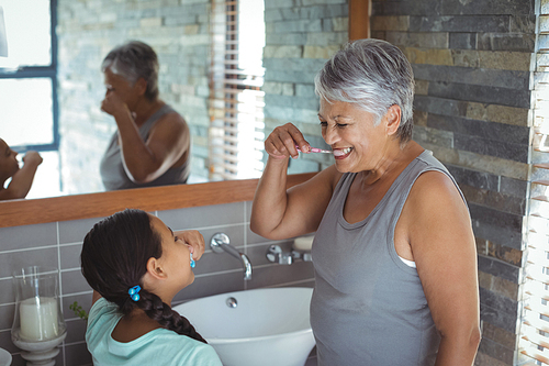 Grandmother and granddaughter brushing teeth in the bathroom at home