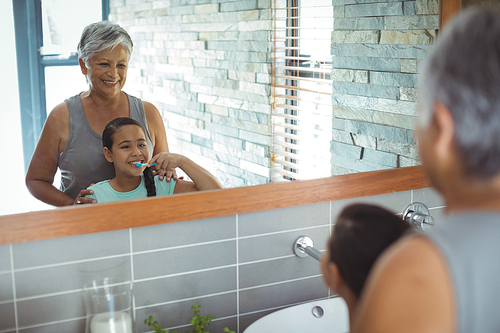 Grandmother and granddaughter brushing teeth in the bathroom at home