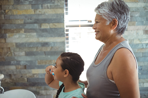 Grandmother and granddaughter brushing teeth in the bathroom at home