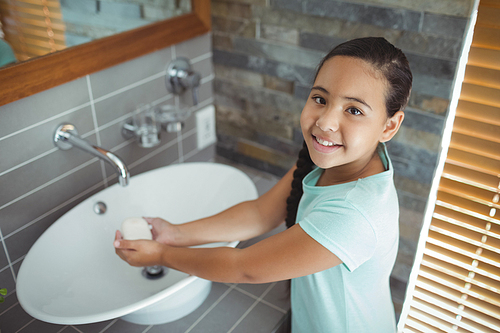Portrait of girl washing hands in bathroom sink at home