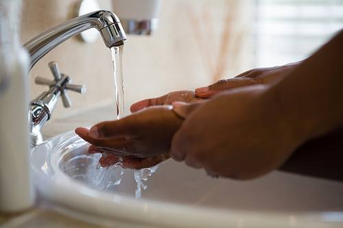 Cropped image of people washing hands in bathroom sink at home