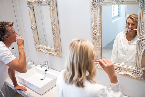 Couple brushing teeth in front of mirror at bathroom