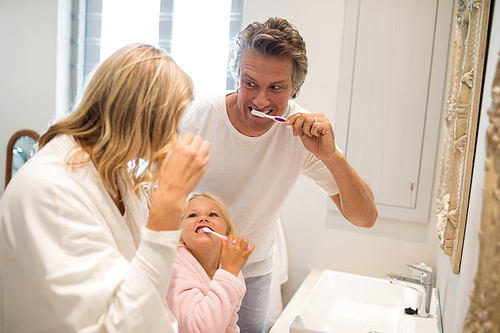 Parents and daughter brushing teeth in bathroom at home