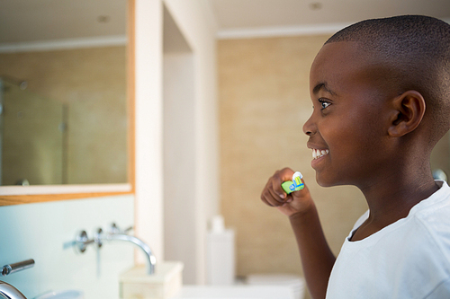 Side view of smiling boy with toothbrush in domestic bathroom