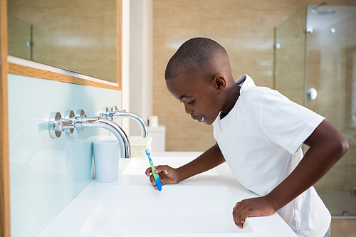 Side view of boy spitting in sink at bathroom