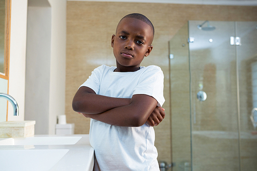 Portrait of boy standing by sink with arms crossed at domestic bathroom