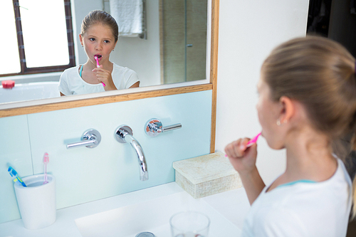 High angle view of girl brushing teeth while reflecting in mirror