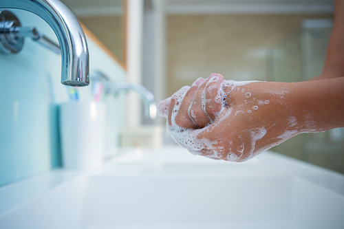 Cropped image of girl washing hands in sink at home