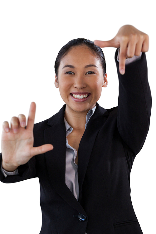 portrait of smiling businesswoman doing finger frame gesture while standing against white background