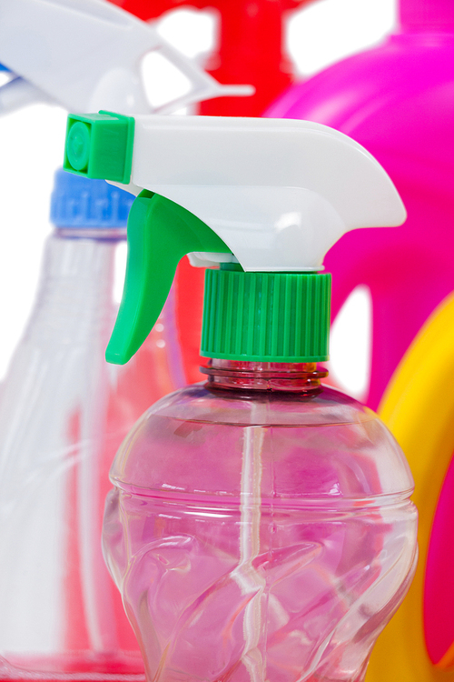Close-up of detergent spray bottle and containers arranged on white background
