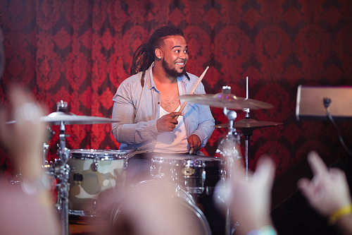 Happy drummer performing on stage at nightclub during concert