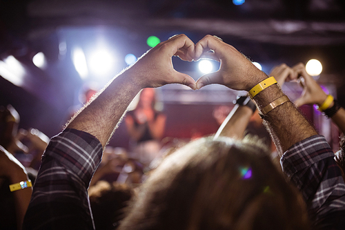Fans making heart shape with hands at nightclub duing music festival