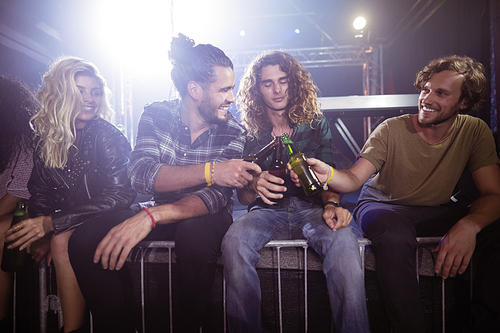 Happy male friends toasting beer bottles at nightclub