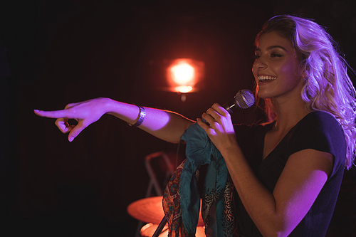 Close up of cheerful female singer pointing while performing in nightclub
