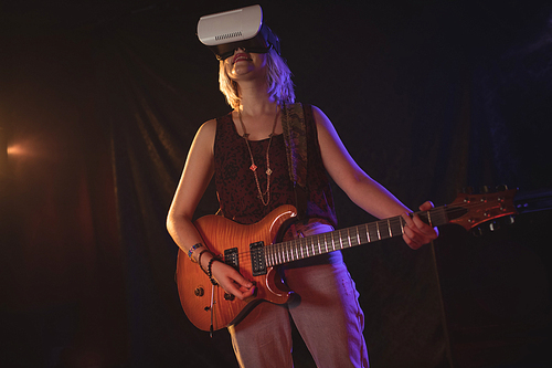 Female guitarist experiencing VR glasses while performing in nightclub
