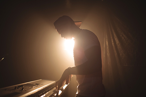 Side view of male musician playing piano in illuminated nightclub