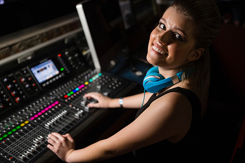 Portrait of female audio engineer using sound mixer in recording studio