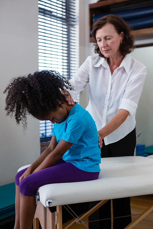 Physiotherapist giving back massage to girl patient in clinic