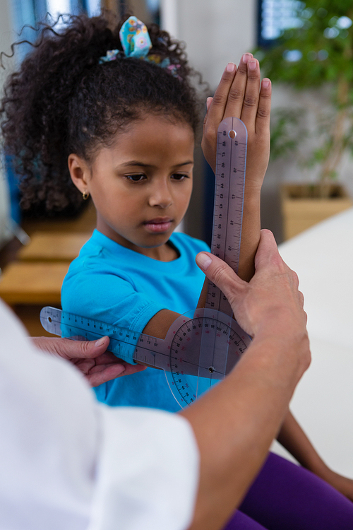 Physiotherapist examining girl patients wrist with goniometer in the clinic