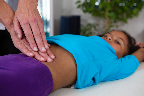 Physiotherapist giving abdomen massage to girl patient in clinic