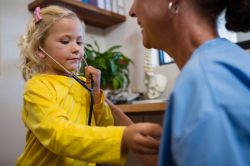 Cute little girl using stethoscope in hospital
