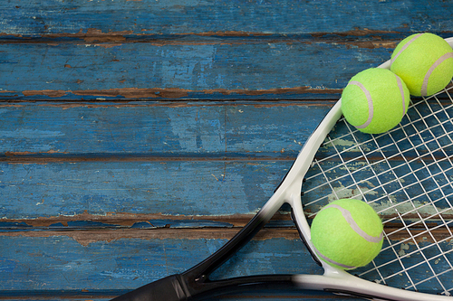 High angle view of tennis racket and balls on wooden table