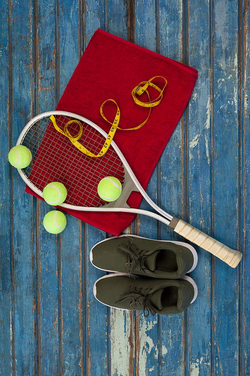 Overhead view of tennis equipment and tape measure on napkin by sports shoes over wooden table