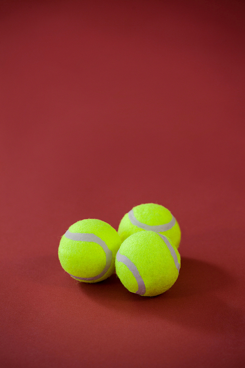 High angle view of three tennis balls on maroon background