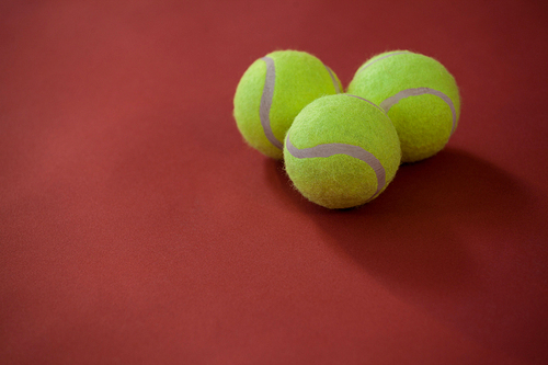 Close up of three tennis balls on maroon background