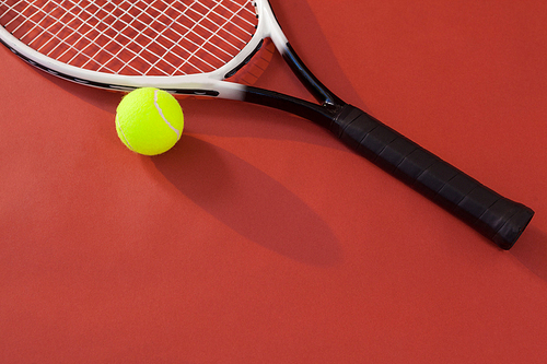 High angle view of tennis racket and ball against maroon background