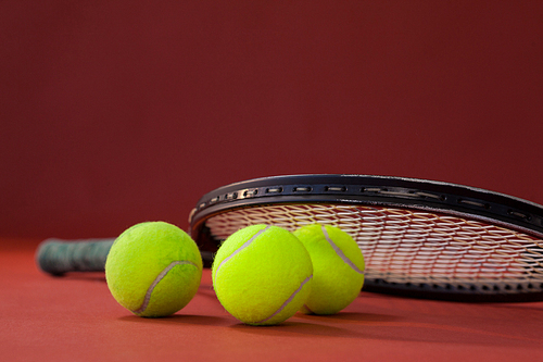 Close up of tennis racket on balls against maroon background