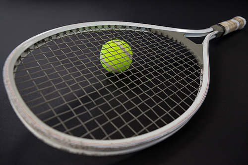 High angle view tennis racket on ball against black background