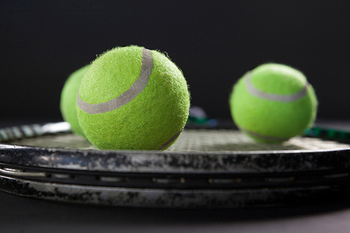 Close up of tennis balls on racket against blackbackground