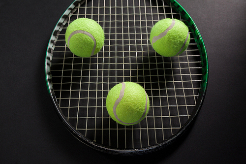 High angle view of balls on tennis racket against black background