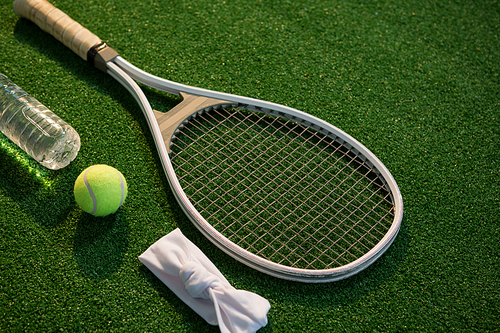 High angle view of tennis ball with racket and napkin by water bottle on field