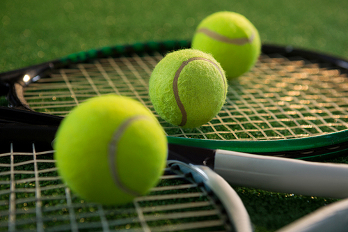 Close up of tennis balls with rackets on field