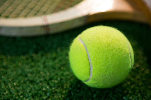 Close up of tennis ball with racket on field