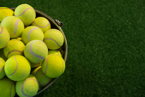 High angle view of fluorescent tennis balls in bucket on field