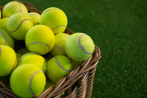 Close up of tennis balls in wicker basket on field