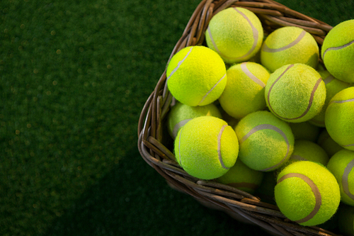 Overhead view of tennis balls in wicker basket on field