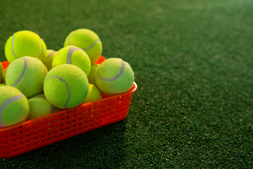 Close up of tennis balls in plastic container on field