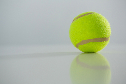 Close up of fluorescent tennis ball against white background