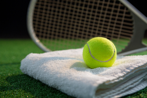 Close up of tennis ball on napkin by racket at playing field
