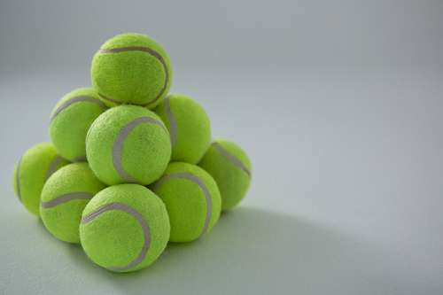 Heap of fluorescent tennis balls against white background