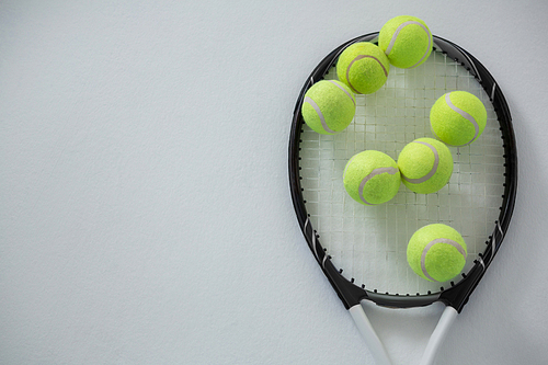 Overhead view of tennis balls on racket against white background